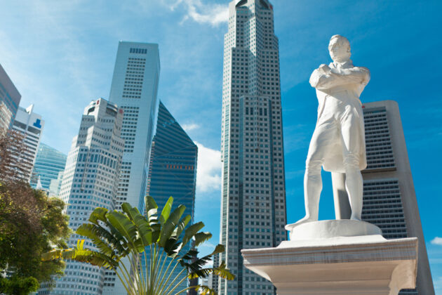 Staty av Sir Raffles med höga skyskrapor i bakgrunden.