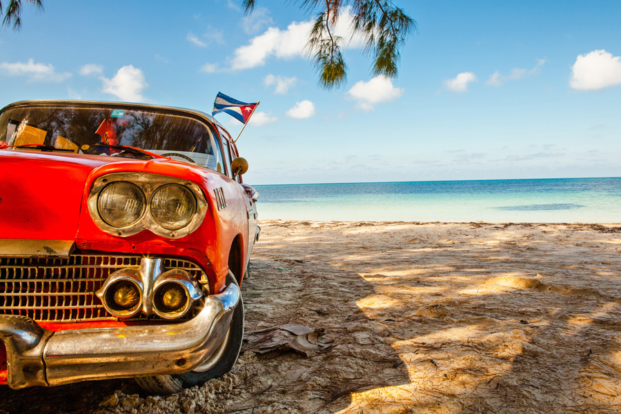 Röd bil på strand på Kuba.