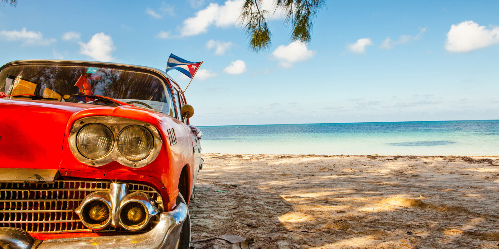 Röd bil på strand på Kuba.
