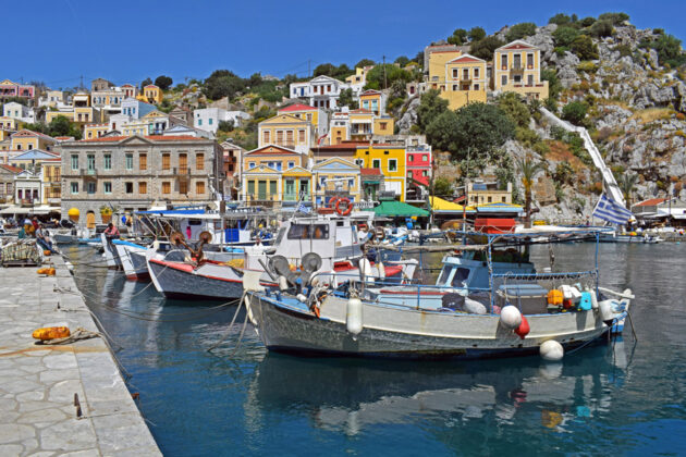 Vackra hus med traditionella fiskebåtar i förgrunden, på Symi i Grekland.